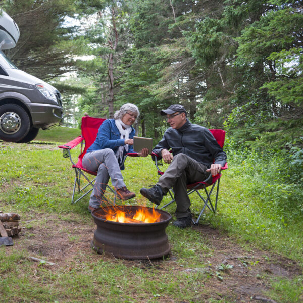 Couple looking at digital tablet near campfire.